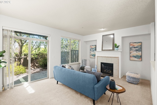 carpeted living room with a tiled fireplace and a textured ceiling