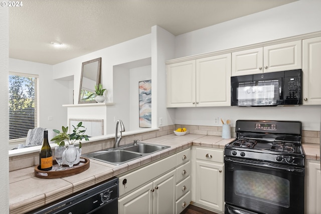 kitchen featuring tile countertops, sink, white cabinetry, and black appliances