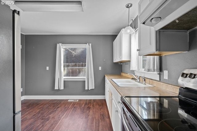 kitchen featuring stainless steel electric range oven, extractor fan, decorative light fixtures, sink, and white cabinets