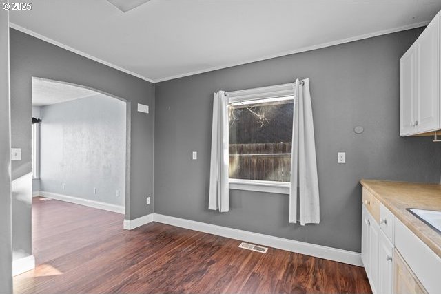 unfurnished dining area featuring dark hardwood / wood-style flooring, plenty of natural light, and ornamental molding