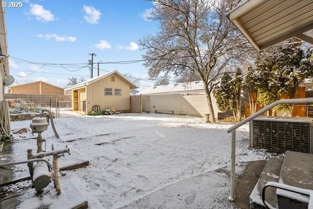 snowy yard with an outdoor structure and central AC