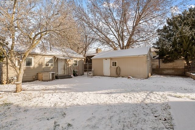 snow covered back of property with a shed