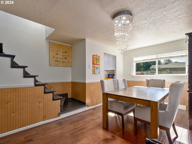 dining area featuring hardwood / wood-style floors, a textured ceiling, and wood walls