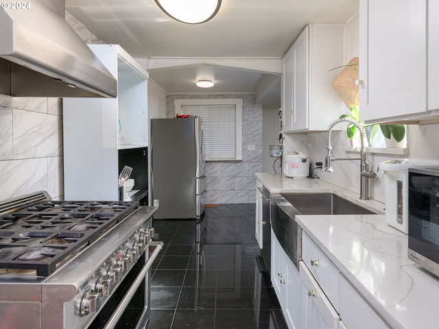 kitchen with white cabinets, range hood, light stone countertops, dark tile patterned flooring, and stainless steel appliances