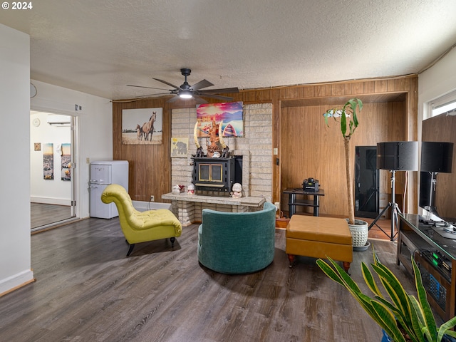 living room featuring ceiling fan, hardwood / wood-style flooring, a textured ceiling, and wooden walls