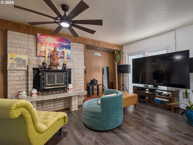 living room featuring dark wood-type flooring, a textured ceiling, and wood walls