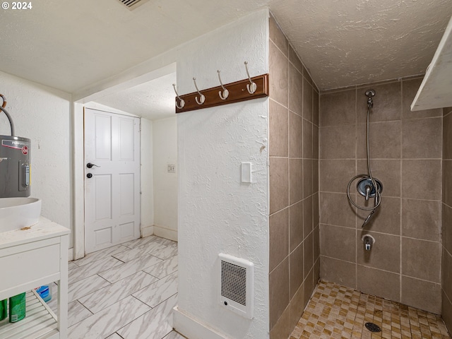 bathroom featuring a textured ceiling, water heater, heating unit, tiled shower, and vanity