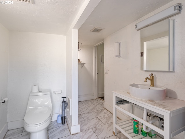 bathroom featuring vanity, a textured ceiling, and toilet