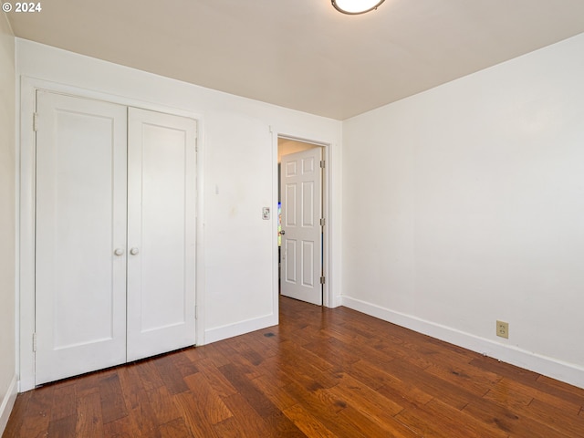 unfurnished bedroom featuring a closet and dark hardwood / wood-style flooring