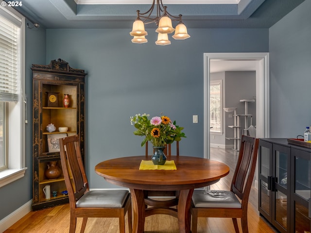 dining room with light wood-style flooring, baseboards, and an inviting chandelier