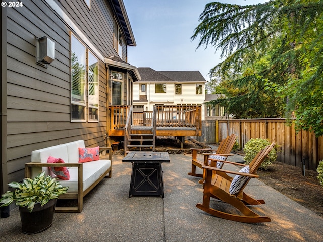 view of patio with an outdoor living space with a fire pit, fence, and a deck