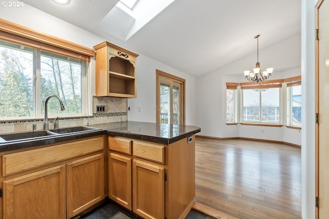 kitchen with an inviting chandelier, kitchen peninsula, a wealth of natural light, and vaulted ceiling