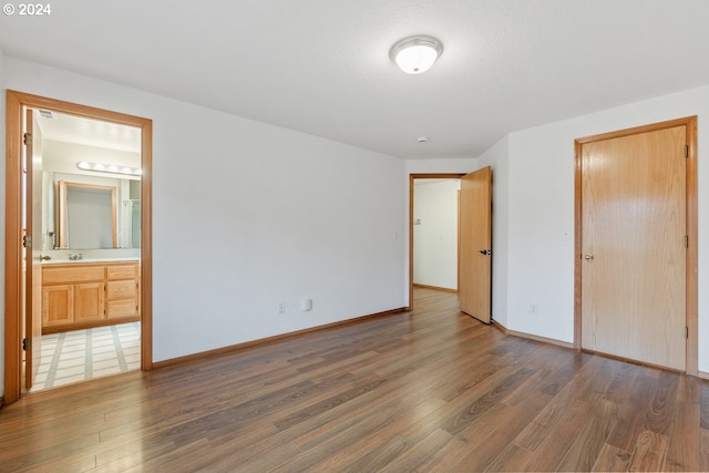 unfurnished bedroom with ensuite bath and dark hardwood / wood-style flooring