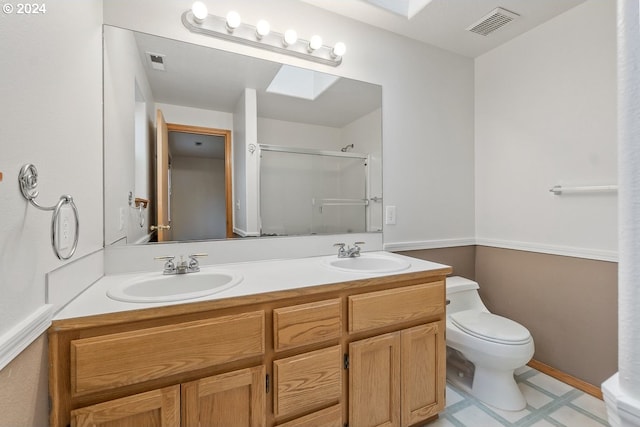 bathroom with vanity, toilet, a shower with door, and a skylight