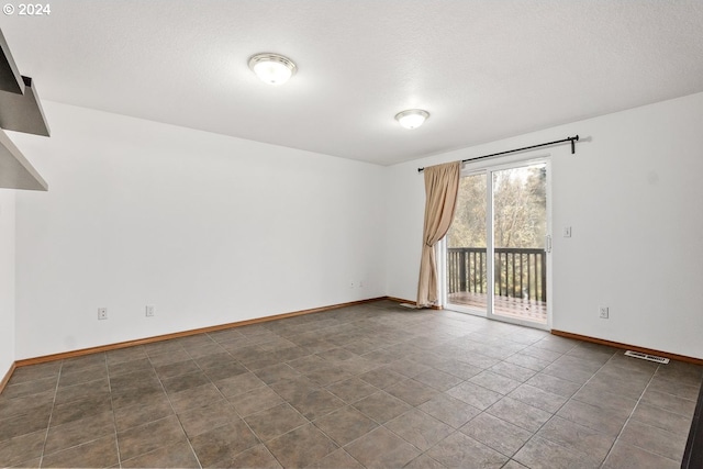 spare room featuring dark tile patterned floors and a textured ceiling