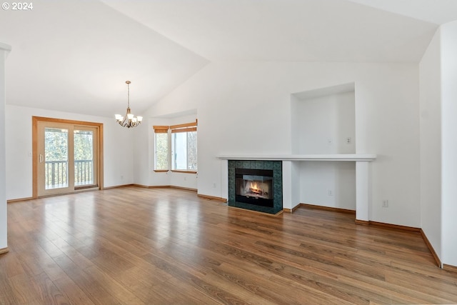 unfurnished living room featuring a tiled fireplace, an inviting chandelier, vaulted ceiling, and hardwood / wood-style flooring