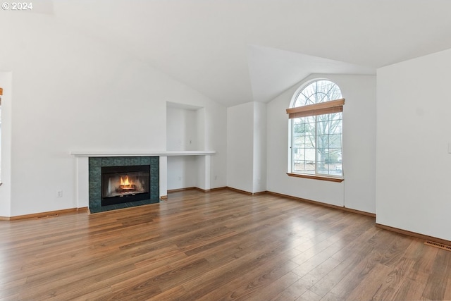 unfurnished living room featuring a tile fireplace, hardwood / wood-style floors, and vaulted ceiling