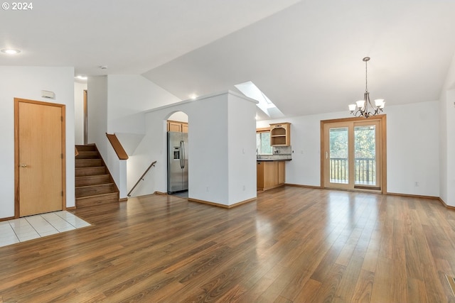 unfurnished living room with hardwood / wood-style floors, an inviting chandelier, and lofted ceiling