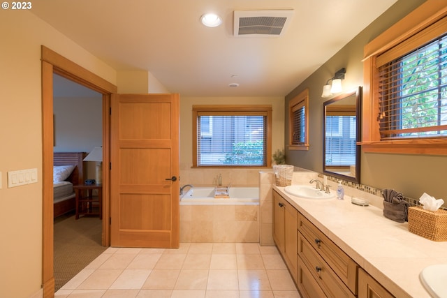 bathroom featuring tiled tub, vanity, tile patterned flooring, and a wealth of natural light