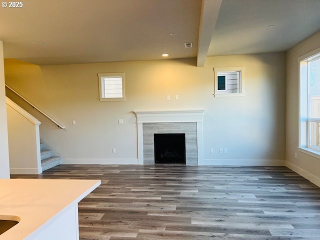 unfurnished living room featuring a tiled fireplace and hardwood / wood-style floors