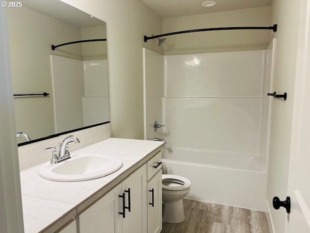 full bathroom featuring vanity, hardwood / wood-style floors, bathing tub / shower combination, and toilet