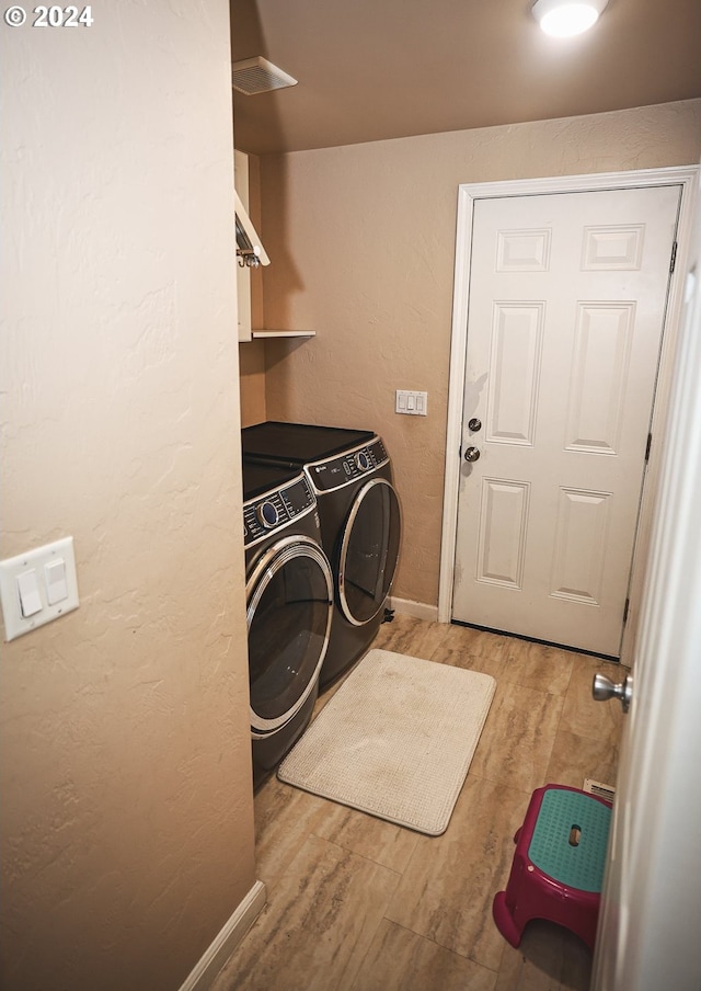 washroom featuring washing machine and dryer and light hardwood / wood-style flooring