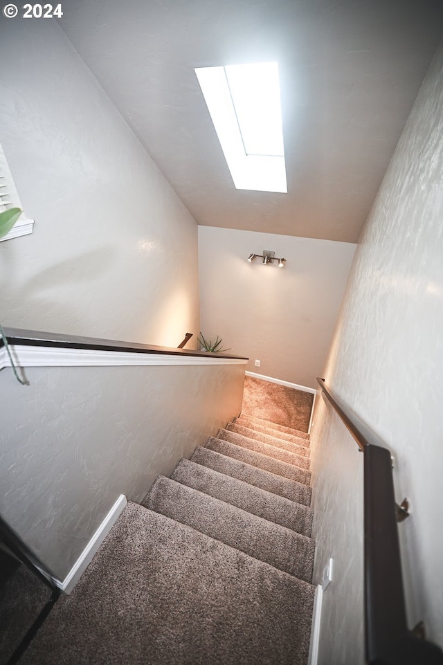 staircase featuring carpet flooring and lofted ceiling with skylight