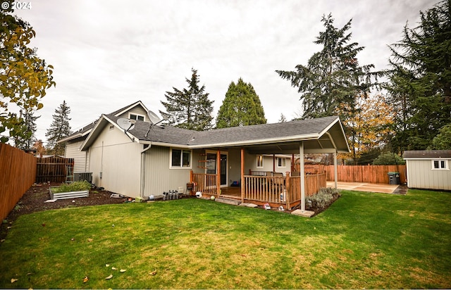 rear view of house with a lawn, cooling unit, a storage shed, and a wooden deck