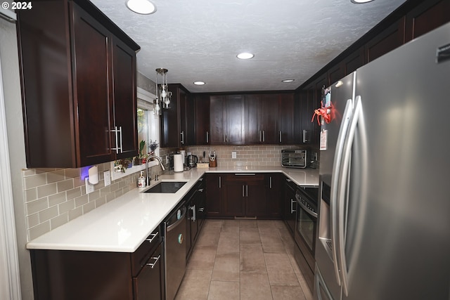 kitchen with sink, decorative backsplash, a textured ceiling, appliances with stainless steel finishes, and decorative light fixtures