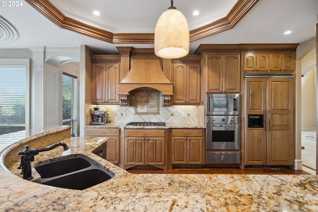 kitchen featuring custom range hood, stainless steel appliances, sink, crown molding, and light stone counters