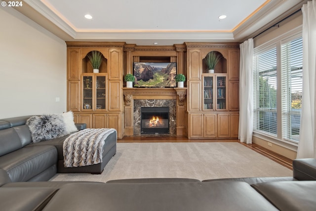 living room featuring a high end fireplace, crown molding, and light hardwood / wood-style floors