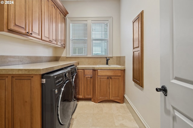 washroom with cabinets, independent washer and dryer, and sink