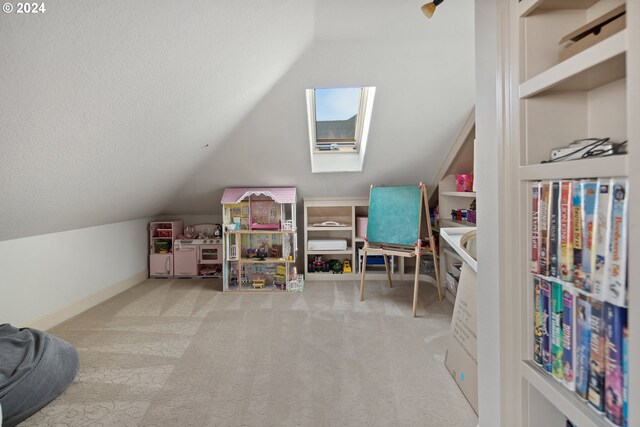 rec room featuring lofted ceiling with skylight, a textured ceiling, and light colored carpet