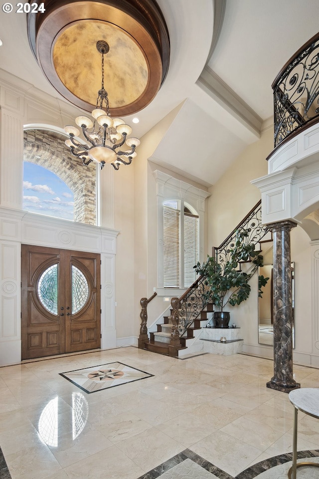 entryway with an inviting chandelier, decorative columns, a high ceiling, and french doors