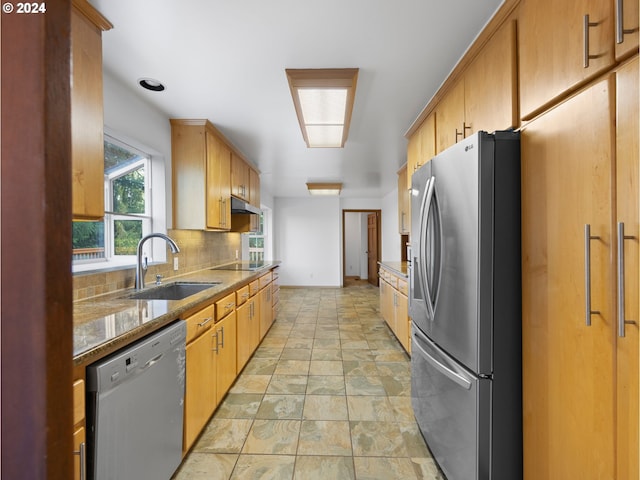 kitchen featuring stainless steel appliances, sink, stone countertops, and backsplash