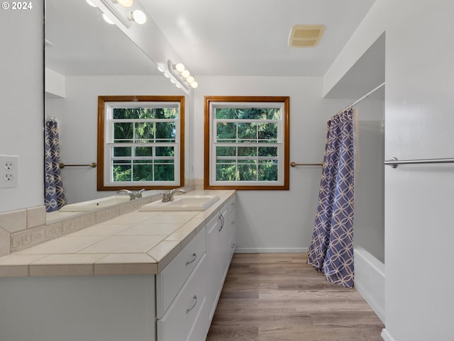 bathroom with vanity, a healthy amount of sunlight, shower / bath combination with curtain, and wood-type flooring