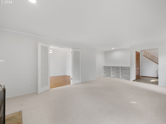 carpeted spare room with ornamental molding and built in shelves