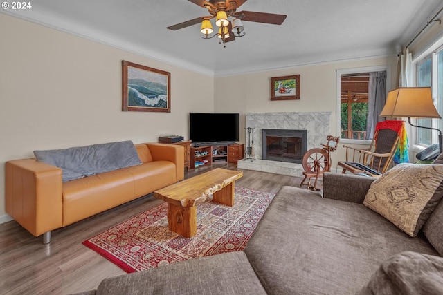 living room with ornamental molding, a fireplace, wood-type flooring, and ceiling fan