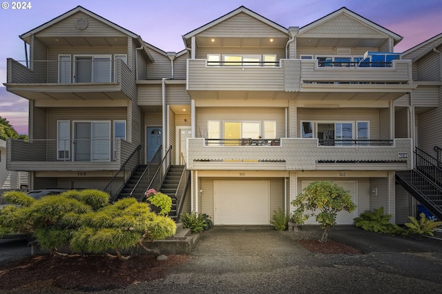 multi unit property featuring a garage, driveway, and stairs