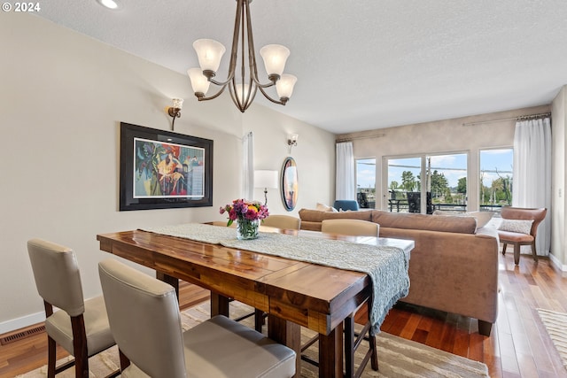 dining area featuring a chandelier, visible vents, baseboards, and wood-type flooring