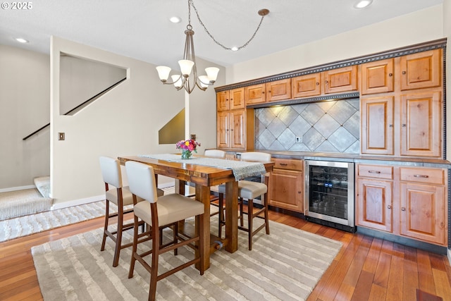 dining room with recessed lighting, wine cooler, light wood-style floors, a dry bar, and a notable chandelier