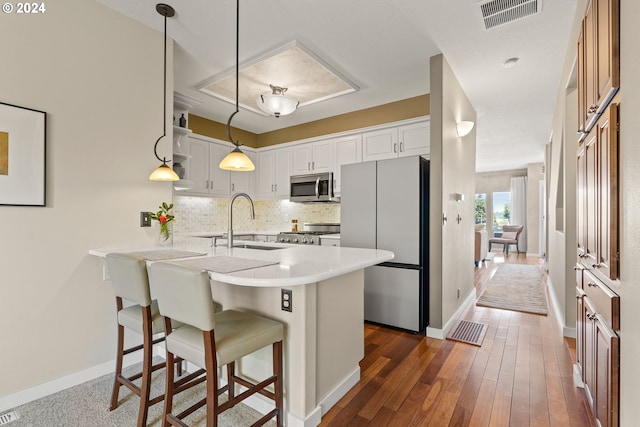 kitchen with visible vents, decorative backsplash, a peninsula, stainless steel appliances, and a sink