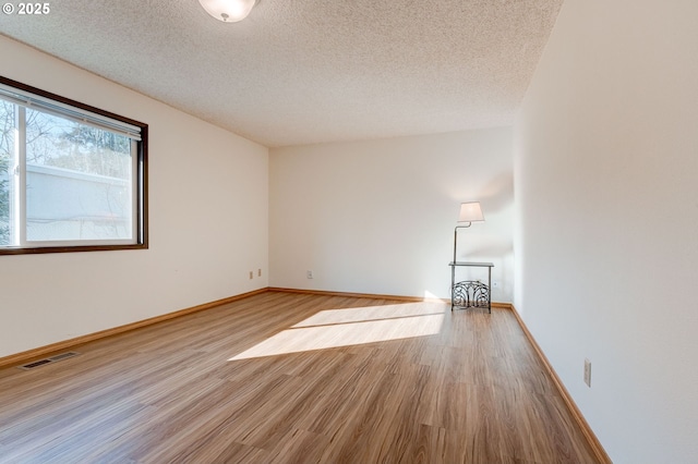 empty room with light hardwood / wood-style floors and a textured ceiling