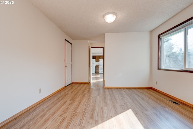 spare room with a textured ceiling and light wood-type flooring