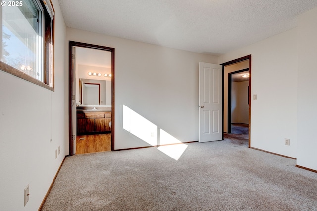 unfurnished bedroom featuring sink, carpet floors, connected bathroom, and a textured ceiling