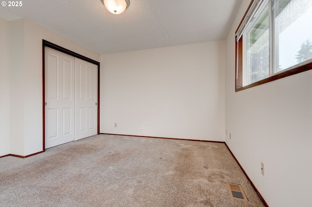 unfurnished bedroom featuring a closet, a textured ceiling, and carpet flooring