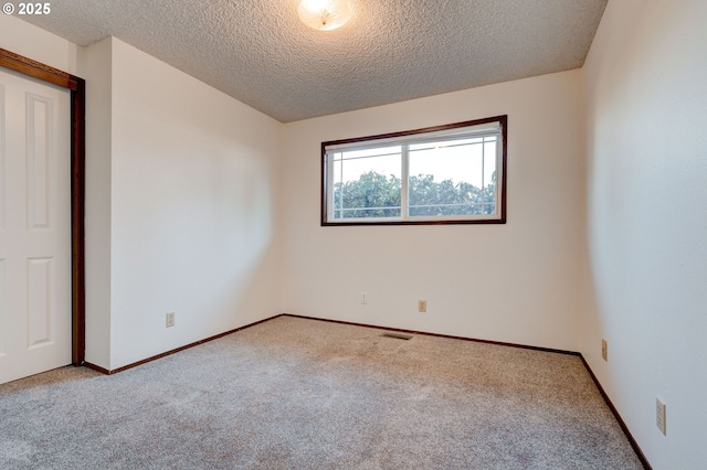 spare room with light colored carpet and a textured ceiling