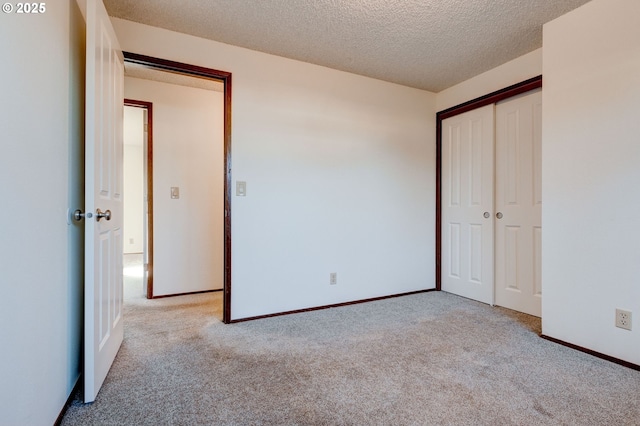 unfurnished bedroom featuring light colored carpet, a closet, and a textured ceiling