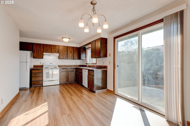 kitchen featuring an inviting chandelier, decorative light fixtures, a textured ceiling, white appliances, and light hardwood / wood-style floors