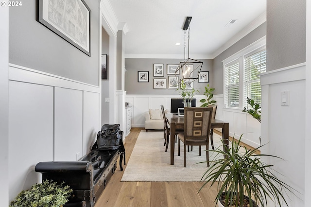 dining room with light wood-type flooring, ornamental molding, and a notable chandelier